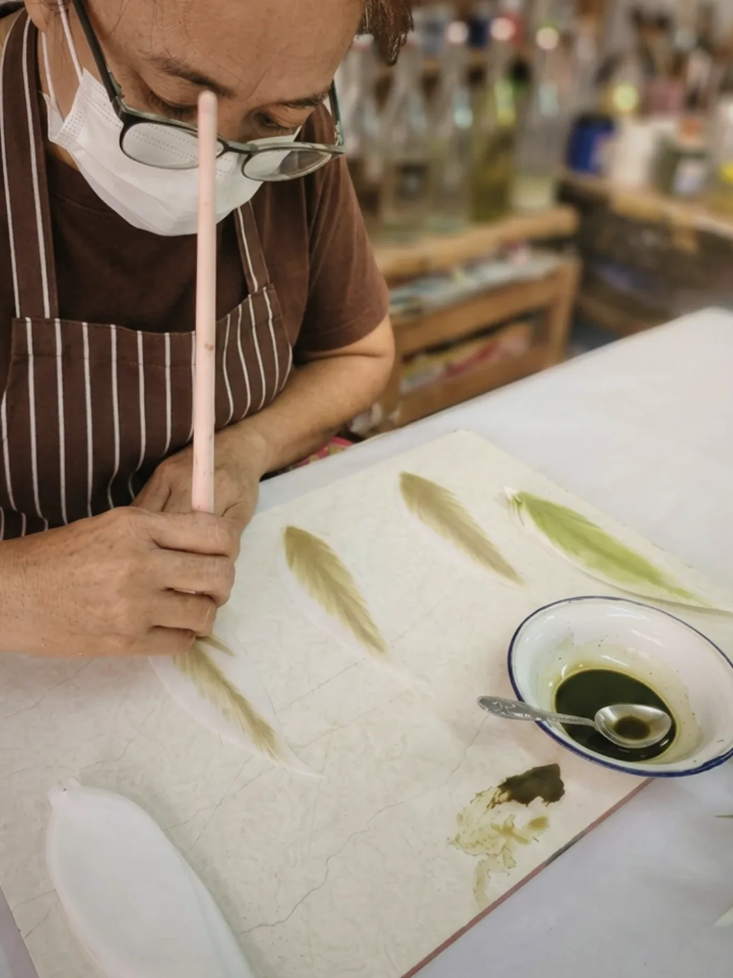 A Foamflora maker hand-painting flower petals at the workshop bench in Bangkok