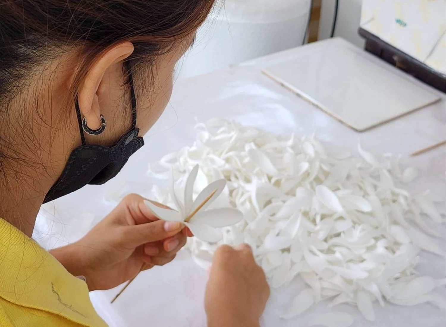 An artisan forming white petals into a tiare flower by hand