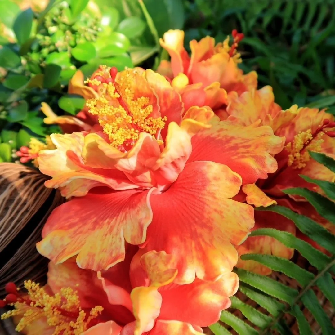 A handmade orange ruffled hibiscus flower among tropical greenery