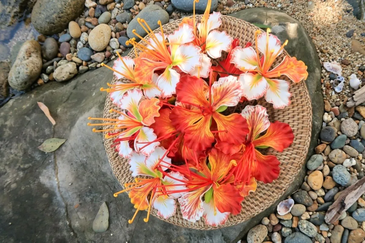 Handmade orange, red and white O’hai Ali’i flowers in a woven basket